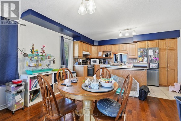 Dining area adjacent to the kitchen with a round wooden table, chairs, and view of the kitchen and living space. - 201 - 770 Principale Street, Casselman