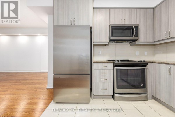 Apartment kitchen featuring stainless steel appliances, light wood-look cabinets, and granite countertops. - 201 - 9191 Yonge Street, Richmond Hill
