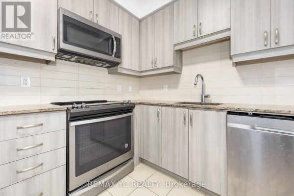 View of an apartment kitchen with stainless steel appliances, light wood cabinets, and a dishwasher. - 201 - 9191 Yonge Street, Richmond Hill