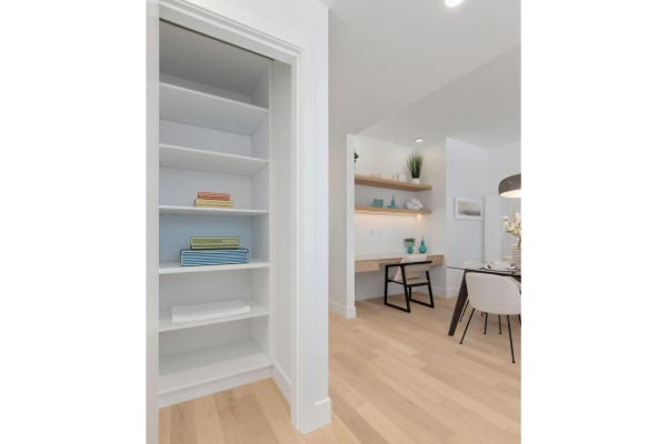 Dining area with glass table, stylish lighting, and wall-mounted shelves with decor. - 201 1475 Foster Street, Surrey