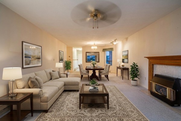 Living room with fireplace, carpeted floor, and large windows. - 201 14957 Thrift Avenue, White Rock