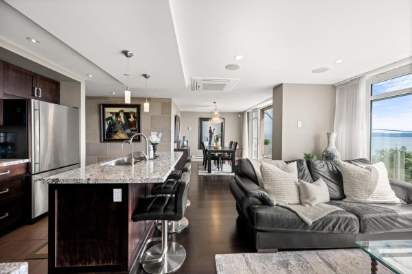 Hallway with a large wall clock, framed artwork, and access to bedrooms. - 201 15097 Marine Drive, White Rock