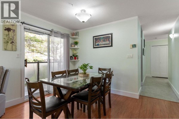 Dining area with glass-top table, chairs, and view of the balcony and hallway. - 201 175 W 4th Street, North Vancouver