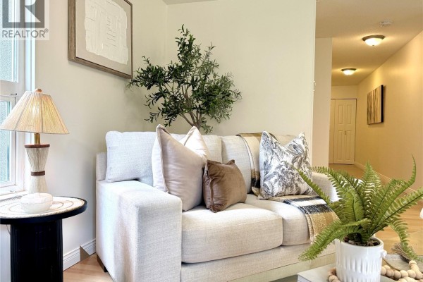 Close-up of a sofa with decorative pillows and a throw blanket, hallway in background. - 201 2520 Wark St, Victoria