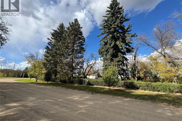 View of a property entrance with mature evergreen trees and a well-maintained hedge border. - 201 2nd Avenue, Borden