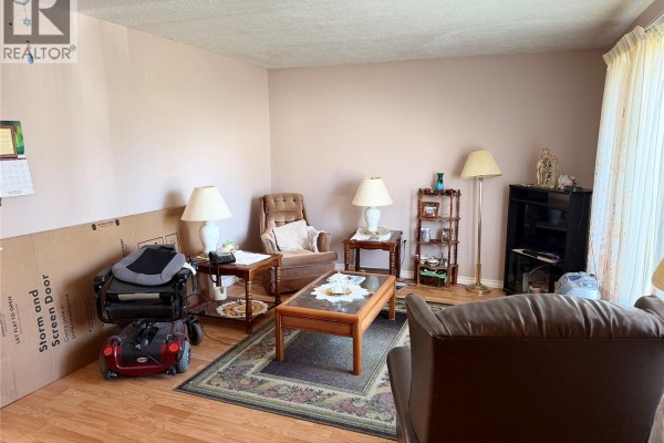 Living room with wood floors, pink walls, and brown furniture. - 201 2nd Avenue, Melfort