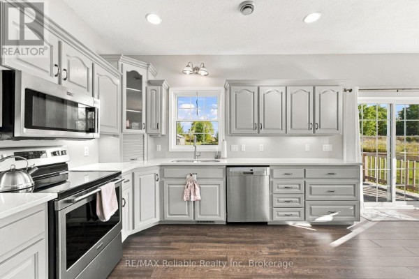 A bright kitchen with light grey cabinets, stainless steel appliances, and dark wood floors. - 201 Cowper Street, Central Huron