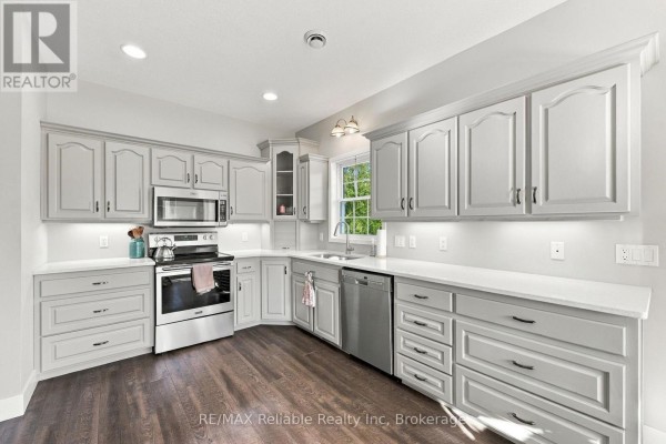 Corner view of a kitchen featuring light grey cabinetry, white countertops, and a window. - 201 Cowper Street, Central Huron