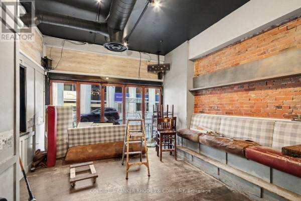 Interior space with brick walls, a long bench seat, and large glass windows. - 201 Queen Street, Ottawa