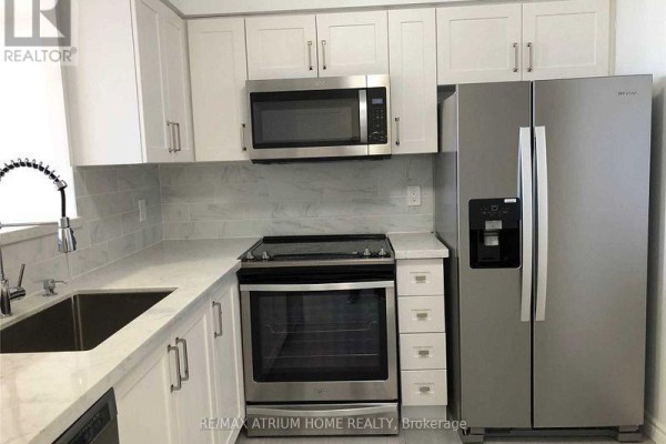 Modern kitchen with stainless steel appliances, white cabinets, and marble countertops. - 2010 - 2627 Mccowan Road, Toronto