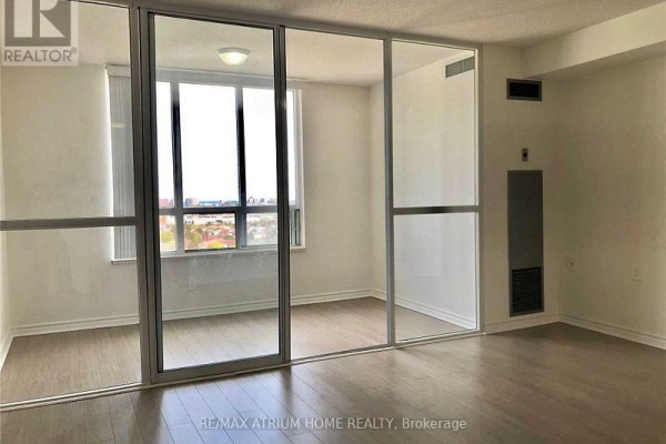 Living area with glass doors opening to a balcony and city views. - 2010 - 2627 Mccowan Road, Toronto