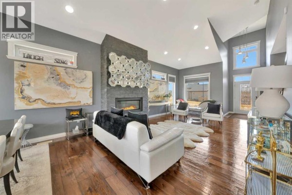 Living room with a stone fireplace, white couch, chairs, and large windows. - 2010 56 Avenue, Lloydminster