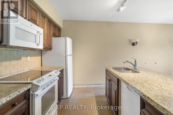 Kitchen with dark wood cabinets, granite countertops, white appliances, and a tiled floor. - 2010/2011 - 90 Highland Drive, Oro Medonte