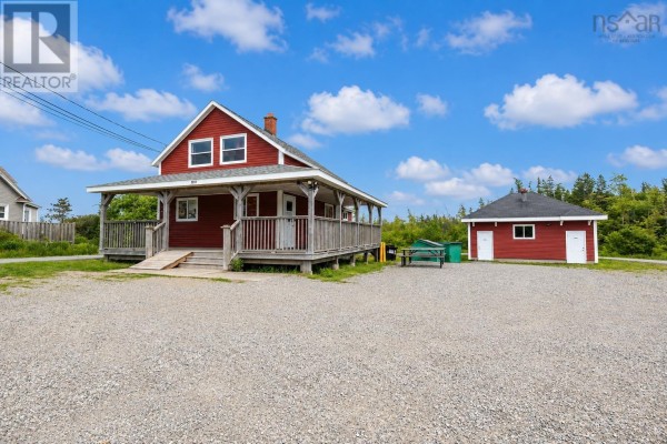 Exterior view of the red commercial building and a small outbuilding on a gravel lot, surrounded by trees. - 2011 Louisbourg Highway, Mira Road