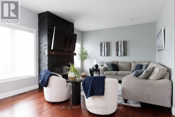 Living room with stacked stone fireplace, TV, sectional sofa, accent chairs, and wood floors - 2014 Ballymote Avenue London North