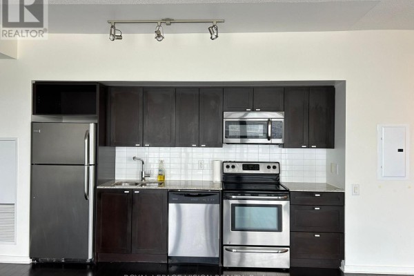 Compact kitchen with dark wood cabinets, stainless steel appliances, and white subway tile backsplash. - 2016 - 105 The Queensway Street, Toronto