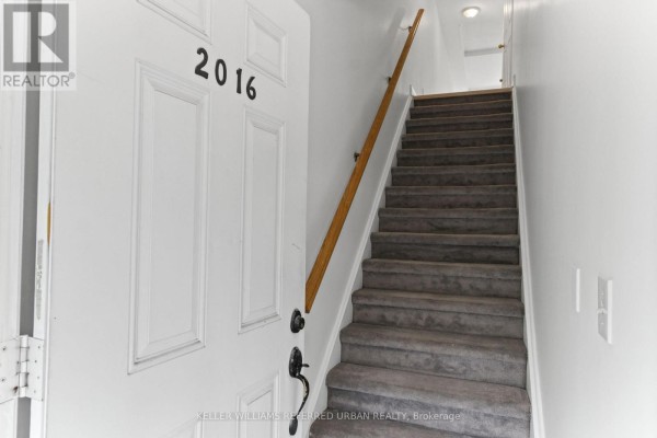 Interior view of the entrance with a white door numbered 2016 and carpeted stairs. - 2016 - 3035 Finch Avenue W, Toronto