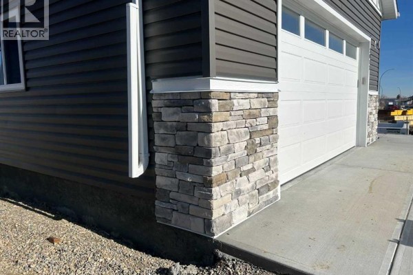 Side view of the house highlighting the garage and snow-covered ground - 2017 30 Avenue, Nanton