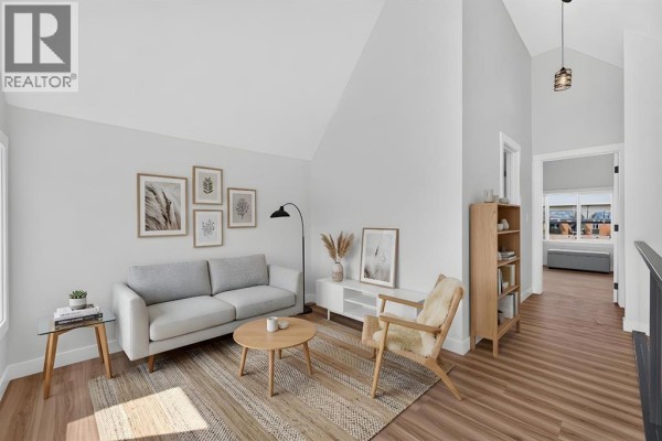 Living room with a vaulted ceiling, light grey sofa, wooden furniture, and artwork on light grey walls. - 2018 12 Avenue Sw, Calgary
