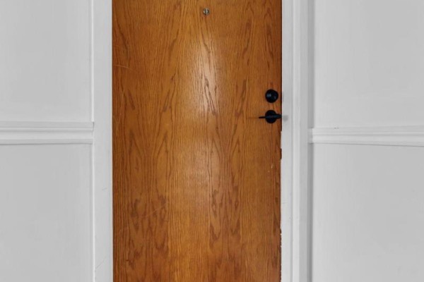 Close-up of a wooden apartment door with a black doorknob and lock. - 202 - 50 Campbell Court, Stratford