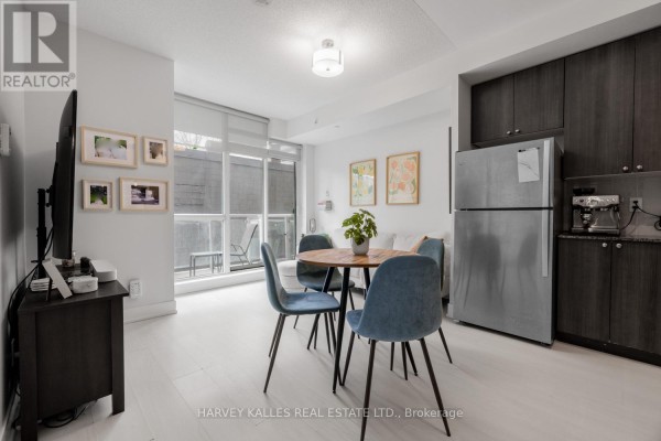 Small balcony with a chair, table, and a view of adjacent brick buildings. - 202 - 68 Merton Street, Toronto