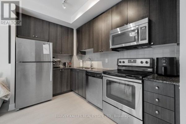 Living room with a white couch, ottoman, television on a dark media stand, and a balcony view. - 202 - 68 Merton Street, Toronto