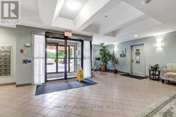 Building lobby with tiled floors, mailboxes, plants, seating, and double glass doors. - 202 - 860 Commissioners Road E, London South
