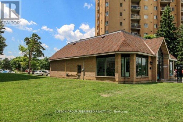 Exterior view of a brick building with large windows, situated on a grassy lawn. - 202 - 860 Commissioners Road E, London South