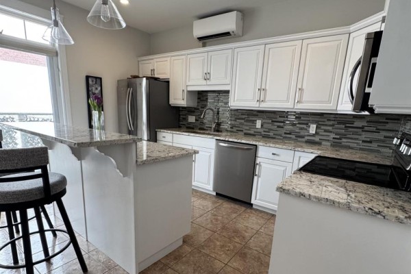 Close-up of kitchen faucet against a glass tile backsplash - 202 111 Richmond Street, Charlottetown