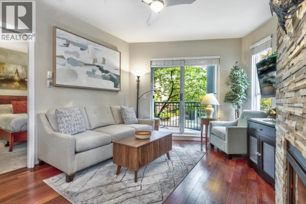 Living room with sofa, coffee table, armchair, and view to balcony. - 202 1928 Nelson Street, Vancouver