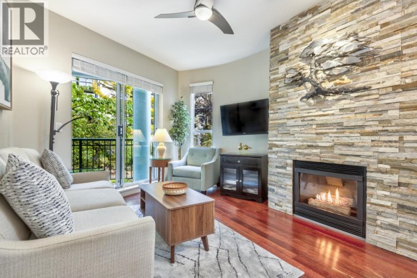 Living room featuring a fireplace, television, and balcony access. - 202 1928 Nelson Street, Vancouver