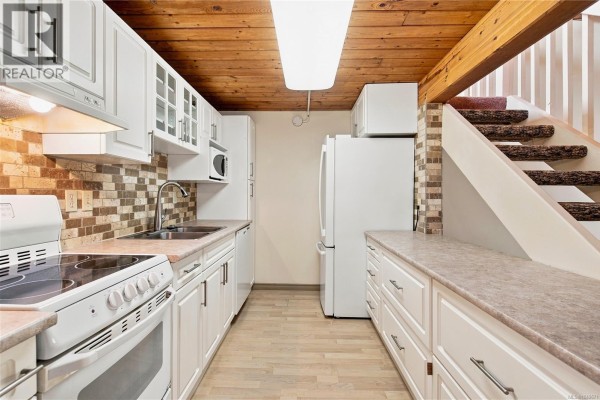 Close-up of a stainless steel double sink and faucet in a kitchen. - 202 3295 Island Hwy W, Qualicum Beach