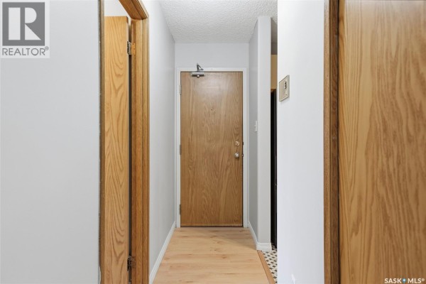 Apartment kitchen with beige cabinets, a white oven, stainless steel refrigerator, and checkered floor. - 202 345 Kingsmere Boulevard, Saskatoon
