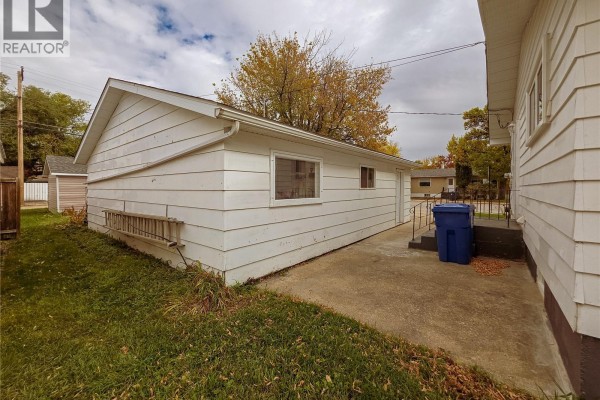 Exterior view of a detached white garage with a concrete pad and a blue bin nearby. - 202 7th Avenue W, Melville