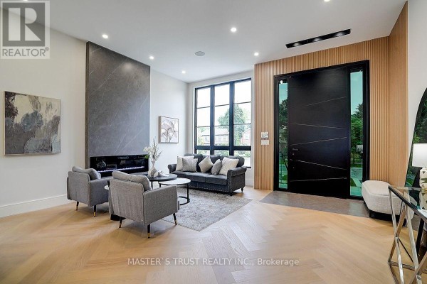 Living room with a grey fireplace, two grey chairs, a dark grey sofa, and wood paneling. - 202 Carlton Road, Markham