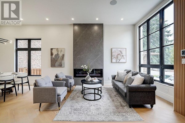 Living room facing a large grey fireplace with a grey sofa and two grey chairs. - 202 Carlton Road, Markham