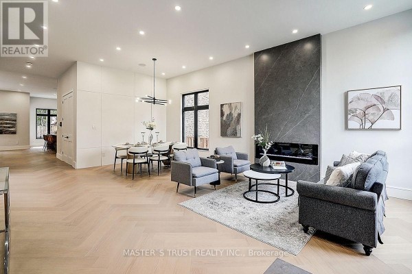 Spacious living and dining area with a fireplace, dining table, and herringbone wood floors. - 202 Carlton Road, Markham