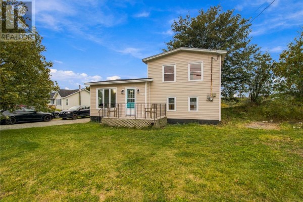 Rear view of a two-story beige house with a green lawn and trees. - 202 Greeleytown Road, Conception Bay South