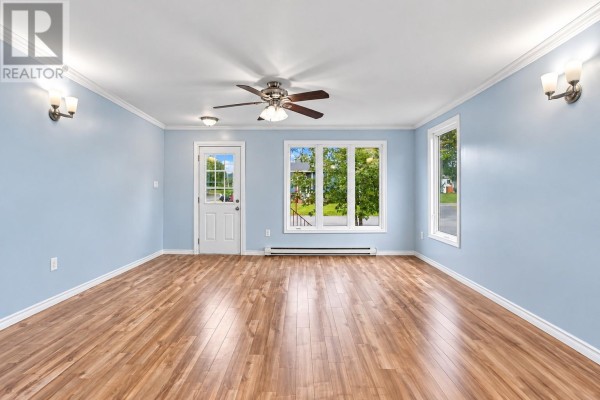 Living room with light blue walls, wood laminate flooring, and a large front window. - 202 Greeleytown Road, Conception Bay South
