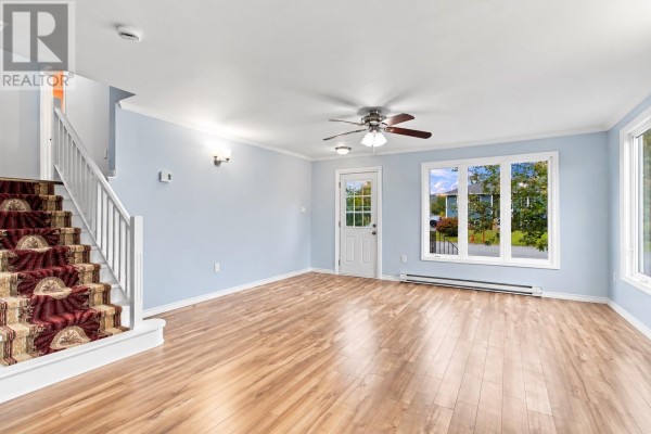 Living room with light blue walls, wood laminate flooring, and a carpeted staircase. - 202 Greeleytown Road, Conception Bay South