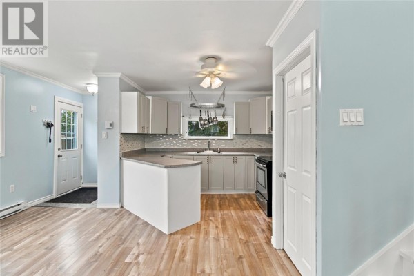 Kitchen with light gray cabinets, a peninsula, and light wood laminate flooring. - 202 Greeleytown Road, Conception Bay South