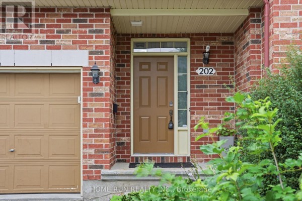 Close-up of the brown front door and brick exterior of the townhouse. - 202 Maxwell Bridge Road, Ottawa