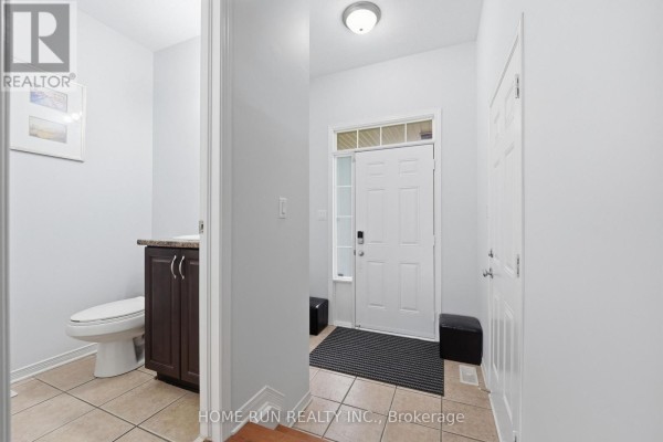 Foyer with tiled floor, white walls, and a door leading to a powder room. - 202 Maxwell Bridge Road, Ottawa