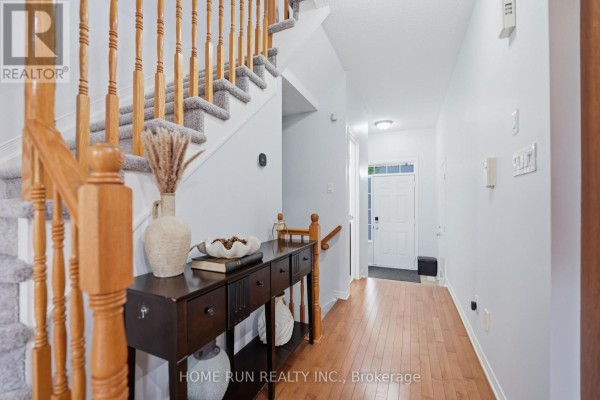 Hallway with wood floors, a console table, and carpeted stairs leading up. - 202 Maxwell Bridge Road, Ottawa