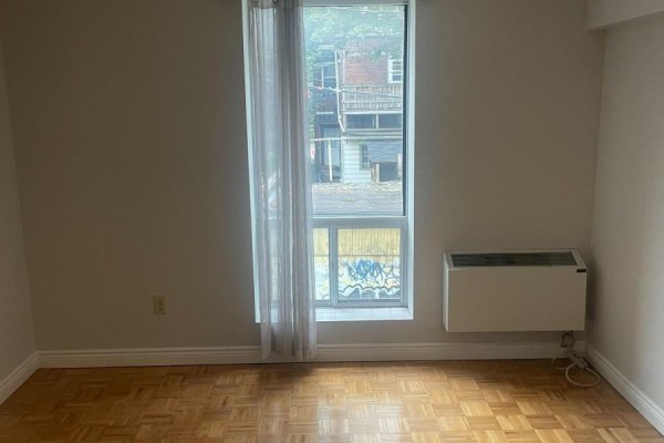 Room with wood parquet flooring, a window with sheer curtains, and a wall-mounted air conditioning unit. - 202 Rear - 13 Grange Avenue, Toronto