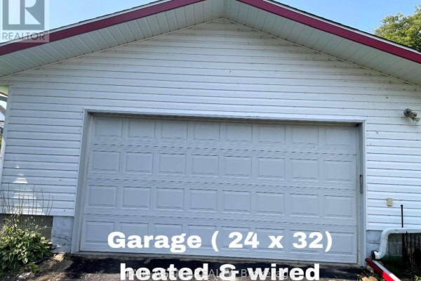 White sectional garage door on a white vinyl-sided garage structure. - 202 Water Street, Thessalon
