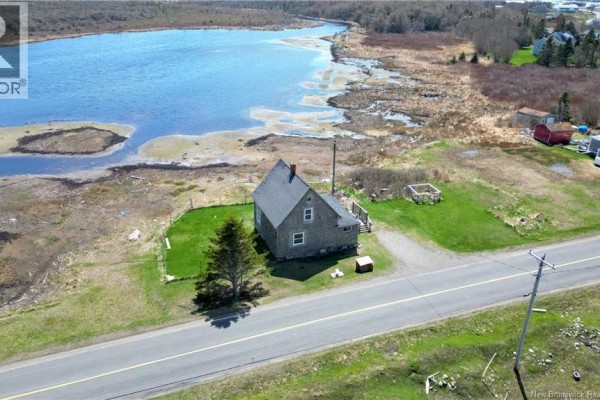 Aerial view of the house and surrounding grassy area with a road and water in the background. - 202 White Head Road, White Head Island