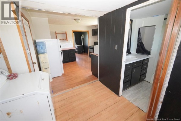 Interior view of a kitchen and bathroom with white appliances, dark cabinets, and wood-look flooring. - 202 White Head Road, White Head Island