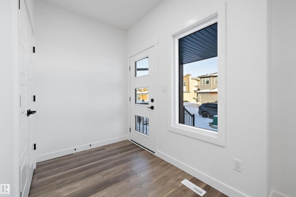 Entryway with white walls, wood-look flooring, and a front door with glass panels. - 2020 191 St Nw, Edmonton