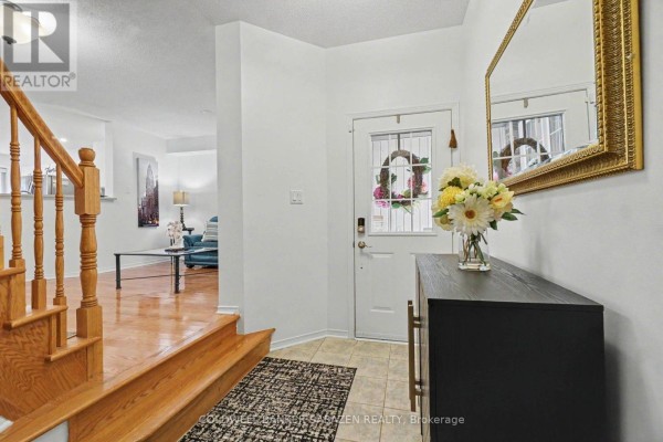 Home entryway with tiled floor, wooden staircase, console table, and a decorative mirror. - 2020 Breezewood Street, Ottawa
